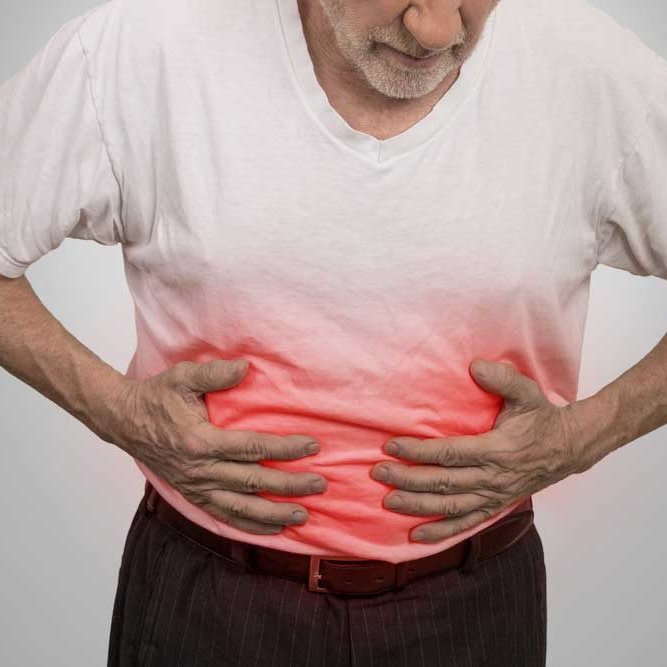 man affected by crohn's disease. he is in pain with hands on his stomach.